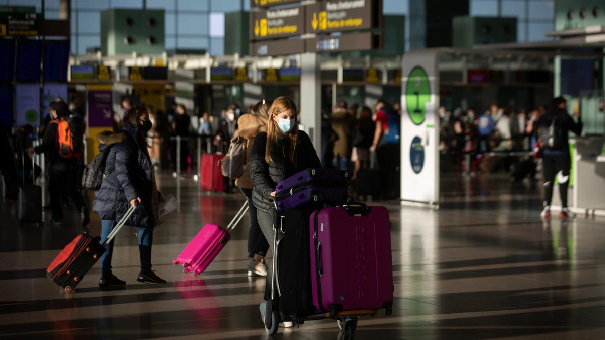 Varios pasajeros con maletas en el aeropuerto de El Prat.