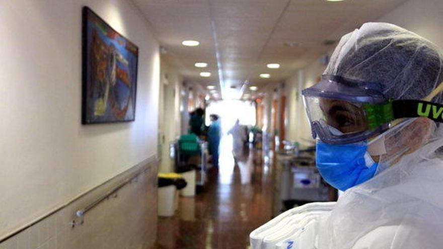 Una professional sanitària de l&#039;Hospital del Mar amb ulleres i mascaretes per protegir-se del coronavirus, en el passadís d&#039;una unitat amb pacients amb covid-19