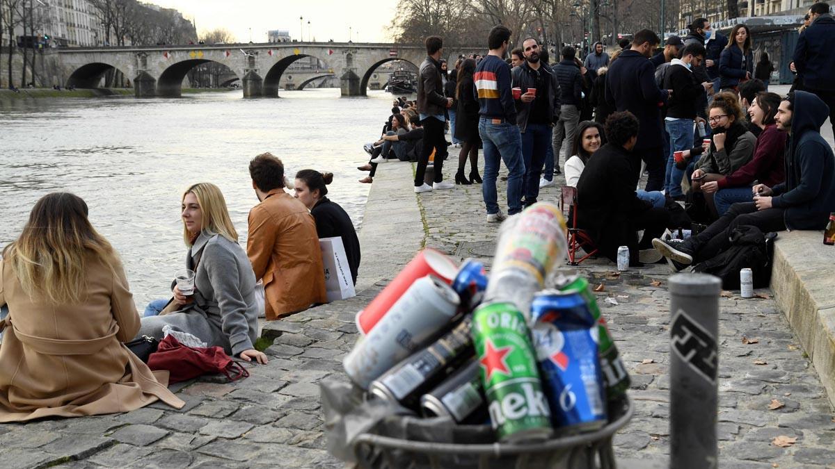 Grupos de jóvenes con bebidas en la rivera del Sena.