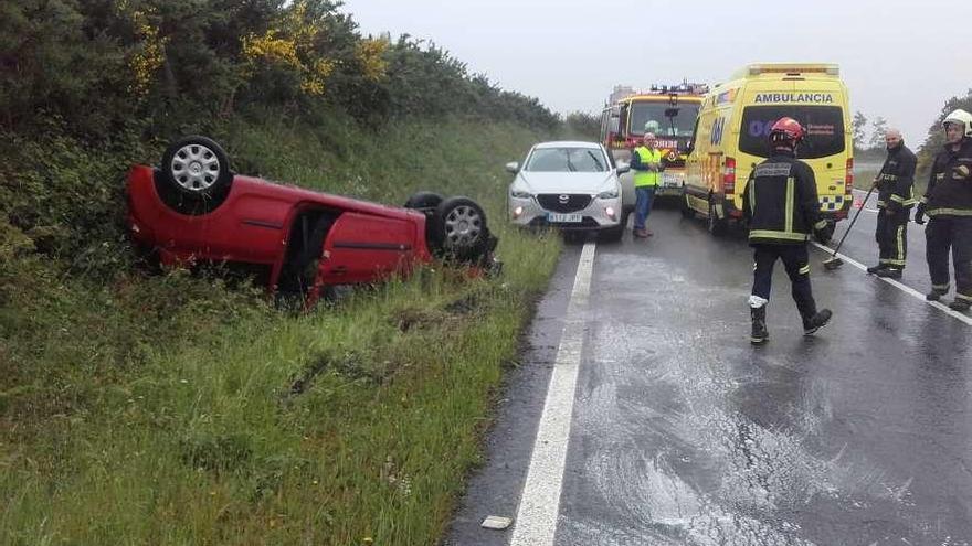 El vehículo volcado y los efectivos de emergencias, ayer, en el vial EP 7201 a su paso por Dúas Igrexas.