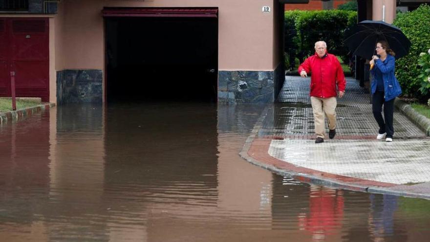 Eloy Martínez con una vecina de la calle Pablo Laloux comprobando las inundaciones de los garajes del número 19 el pasado día 15.