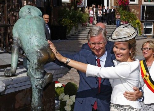 Belgium's Queen Mathilde and King Philippe touch a statue called 'Maca' during their Joyous Entry in the province of  Walloon Brabant in Wavre