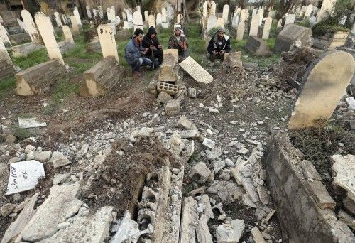 Free Syrian Army fighters pray around a grave damaged by a mortar shell fired by Syrian Army soldiers at the Mleha suburb of Damascus
