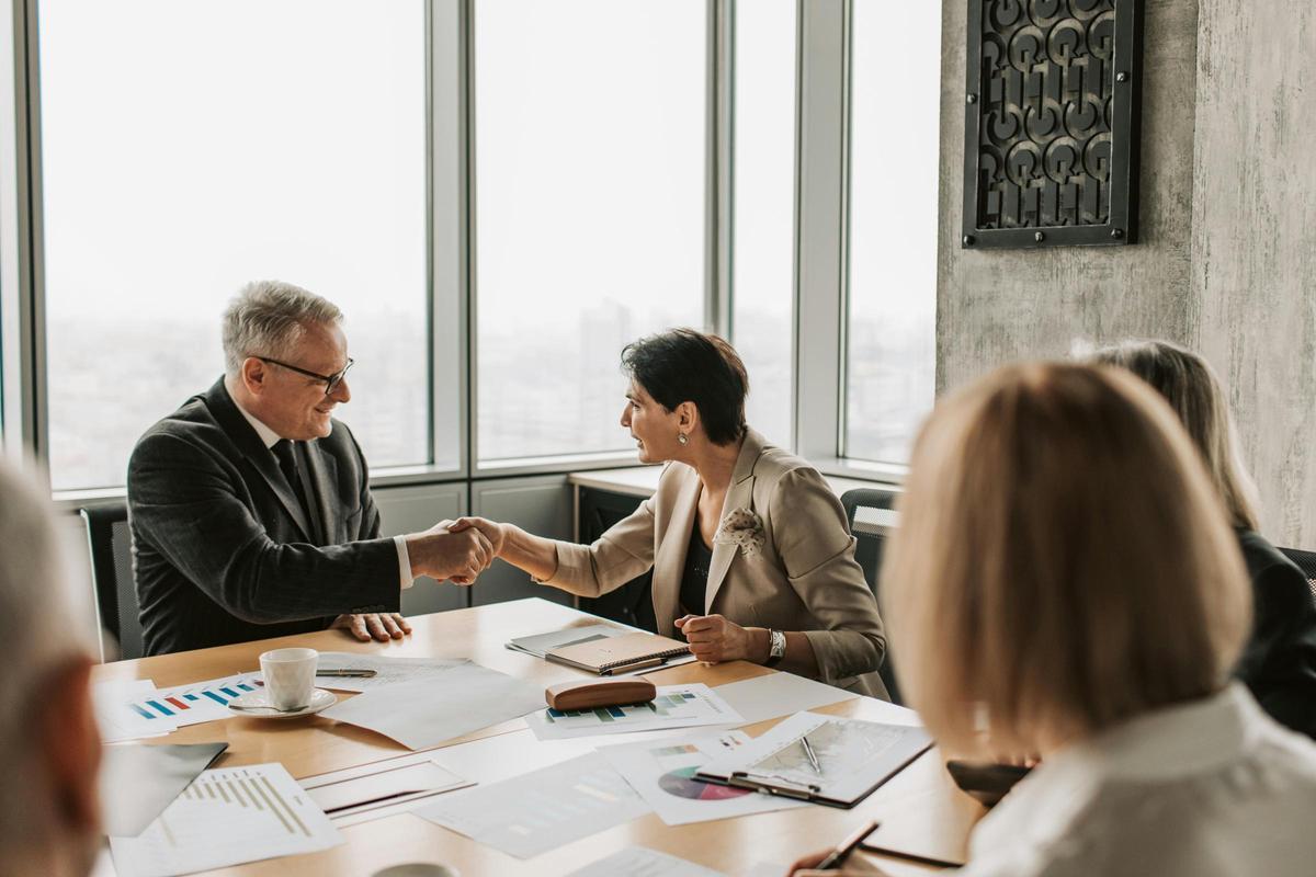 Dos personas se estrechan la mano en una reunión de trabajo.
