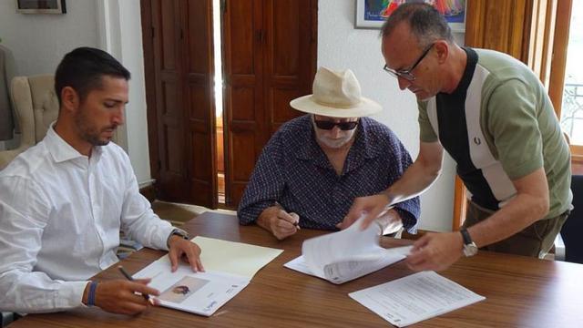 El autor firma el convenio para ceder algunas de sus obras.