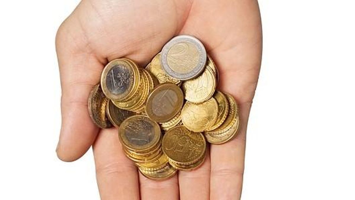 Una persona sostiene en la mano varias monedas, de 2 euros y de otras cantidades.