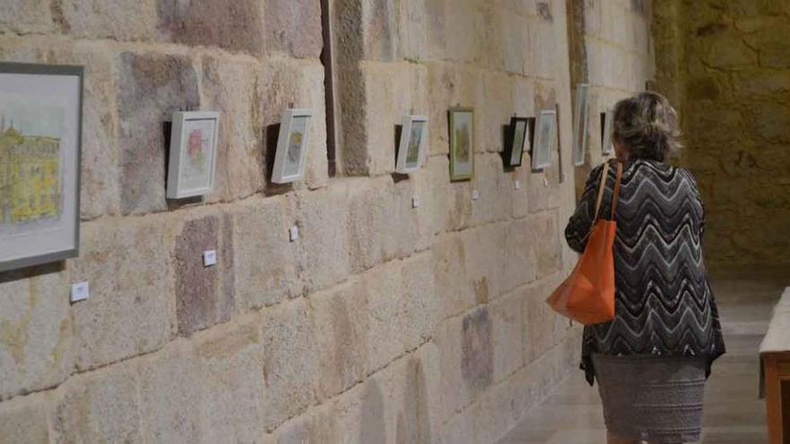 Una mujer contempla las acuarelas expuestas en el claustro del Seminario.