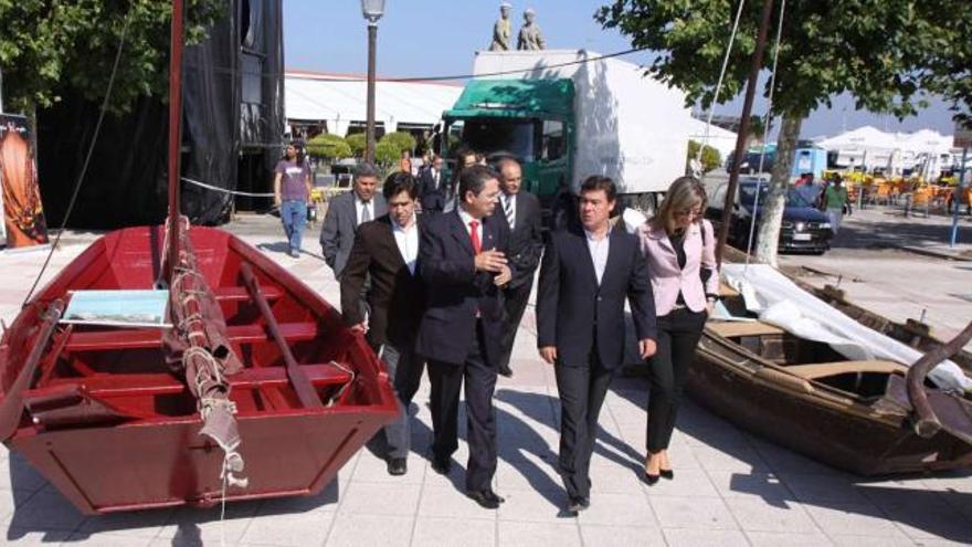 Miguel Pérez (1º i.) pasea entre embarcaciones tradicionales por O Corgo, el lugar elegido para el museo de la carpintería de ribera.  //  Muñiz