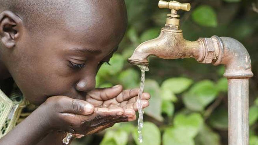 Un niño bebe agua de una fuente.