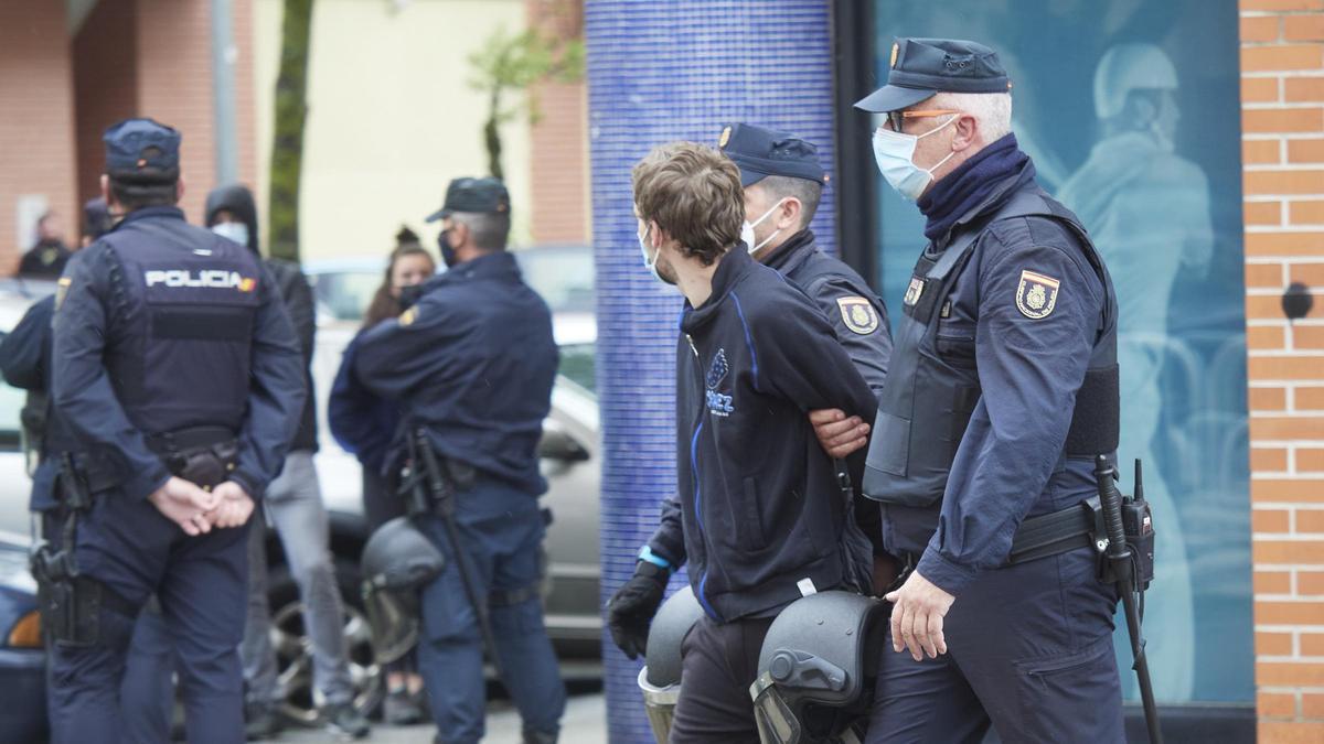 Dos agentes de Policía Nacional llevan detenido a un miembro de Gazte Koordinadora Sozialista.