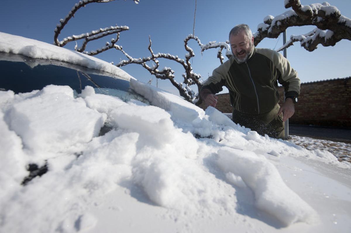 Un caballero retira la nieve acumulada en su coche, en La Palma d’Ebre (Ribera d’Ebre).