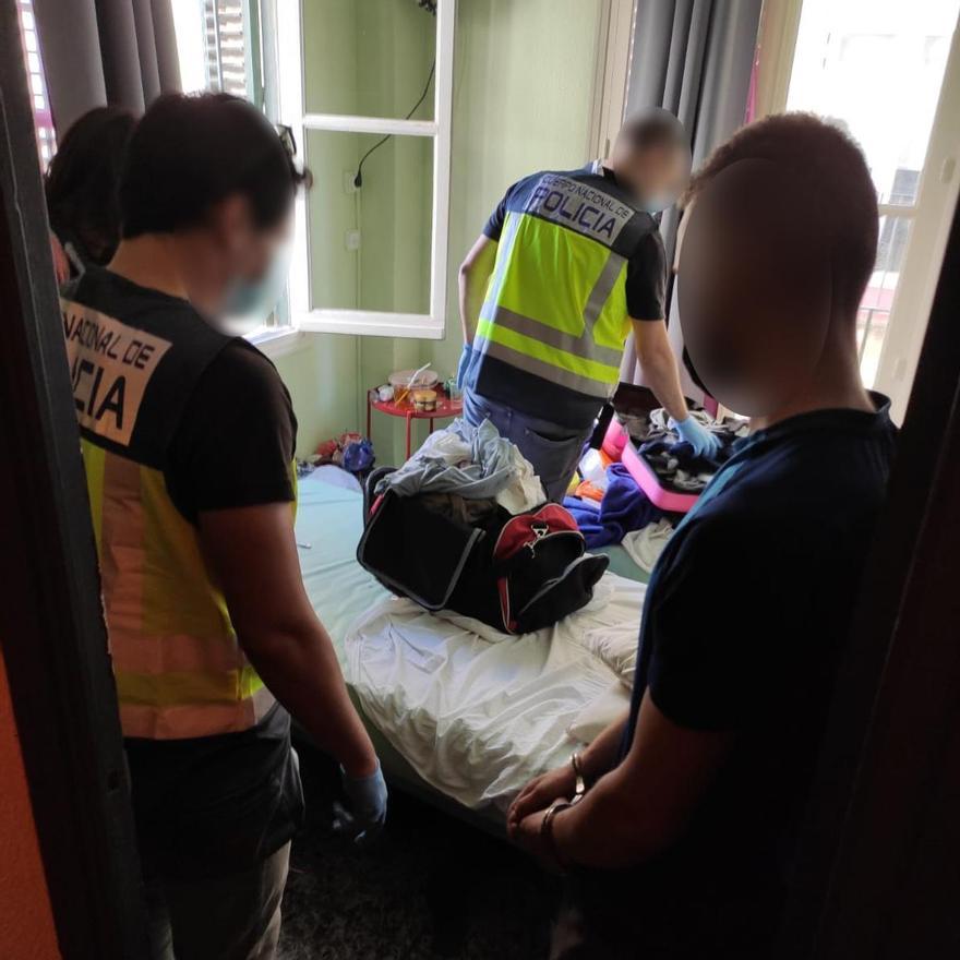 El detenido, a la derecha, presencia el registro policial de su habitación en Alicante.