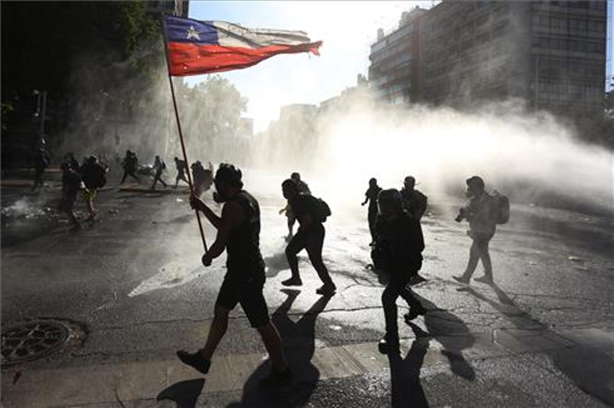 Miembros de carabineros dispersan a los manifestantes lanzando agua durante las protestas en contra del Gobierno.