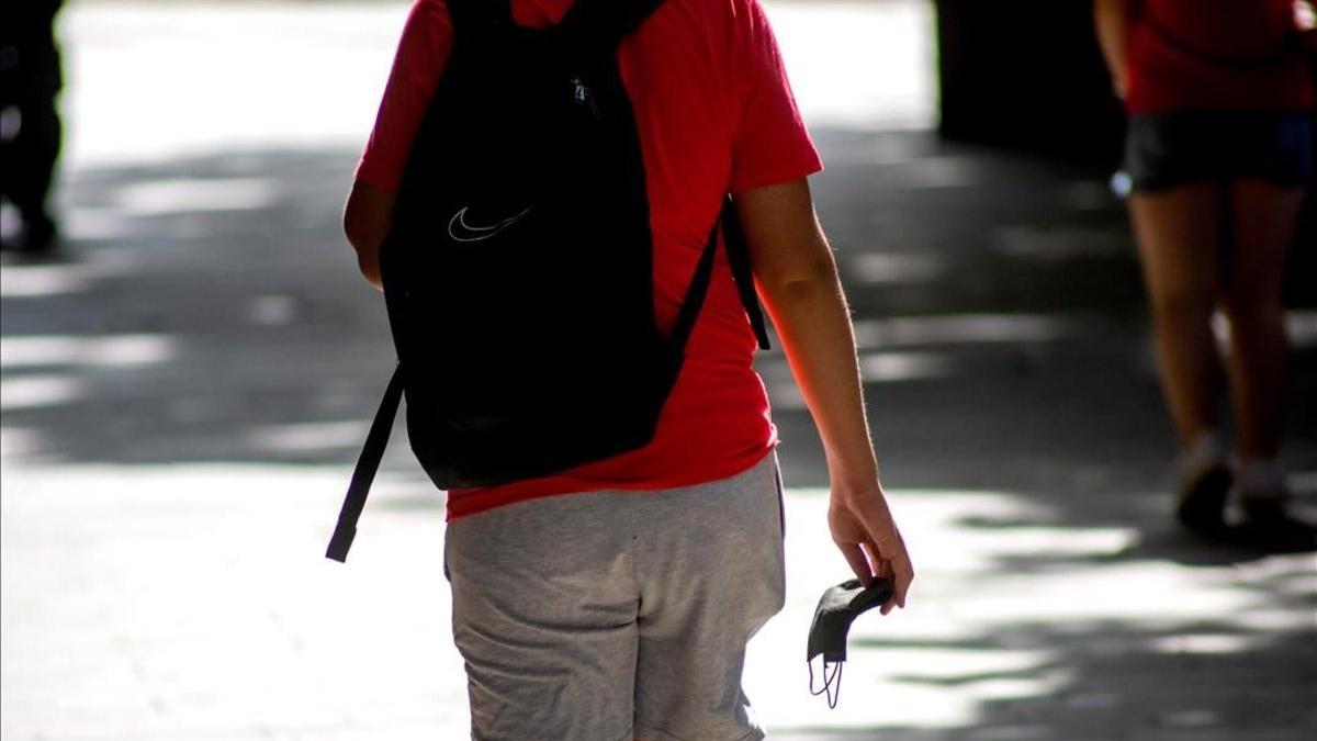 Un hombre pasea con la mascarilla en la mano por las calles de Lleida