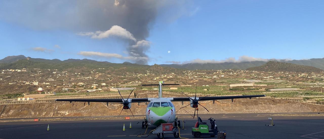 Un avión de Binter en la pista del aeropuerto de La Palma, con el volcán en erupción al fondo