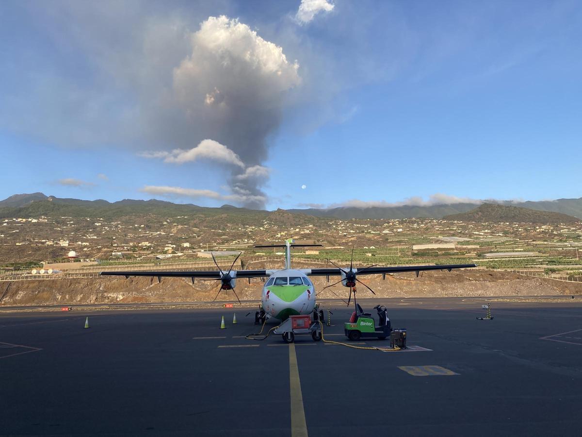 Un avión de Binter en la pista del aeropuerto de La Palma, con el volcán en erupción al fondo.