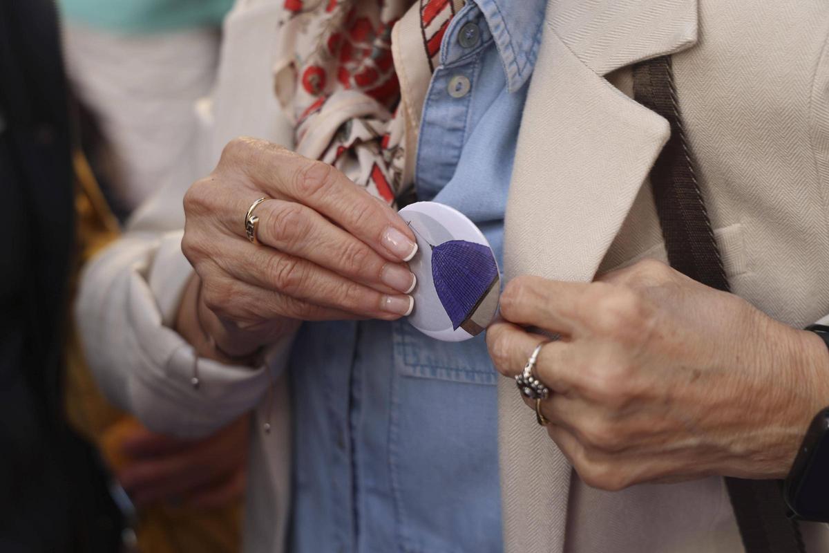 Una mujer se coloca la chapa identificativa del colectivo Semana Santa Inclusiva de Sagunt.
