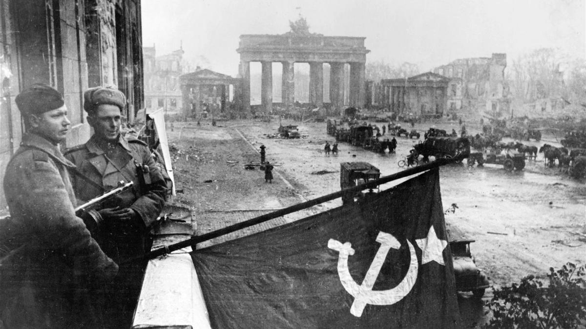Soldados sovieticos levantan una bandera desde un balcón.