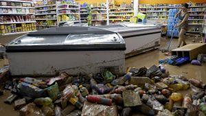 Una mujer limpia su comercio afectado por las inundaciones del 29 de octubre