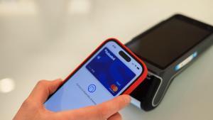 Una persona pagant amb una targeta del Banc Sabadell al telèfon mòbil en un establiment