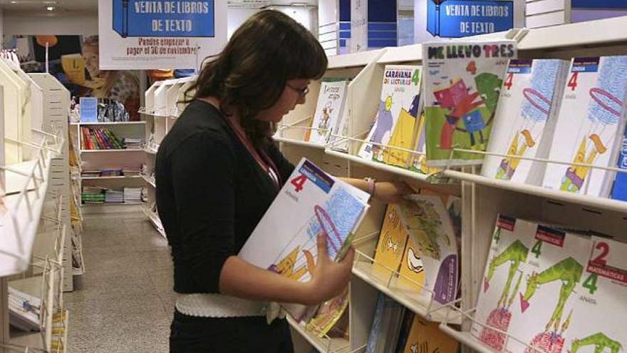 Una joven ojea libros de texto en un comercio. / josé huesca