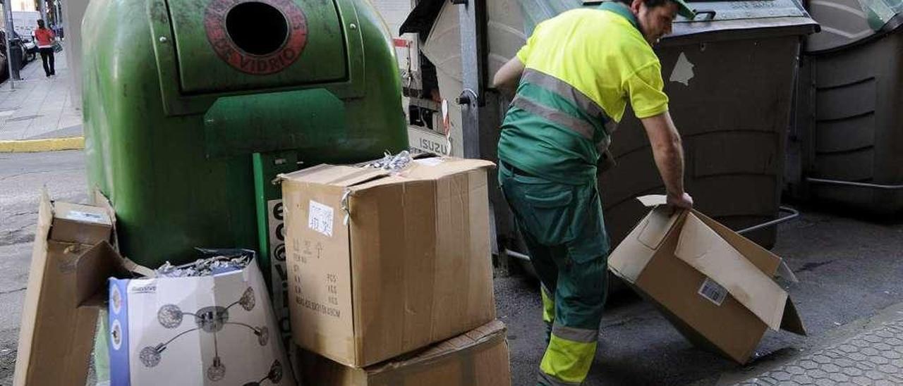 Un operario retira cajas de cartón apiladas junto a contendores, en Lalín. // Bernabé/Javier Lalín