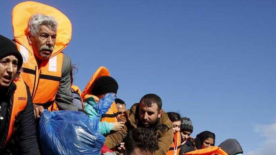 Varios refugiados son ayudados a bajar de una barca en Lesbos.