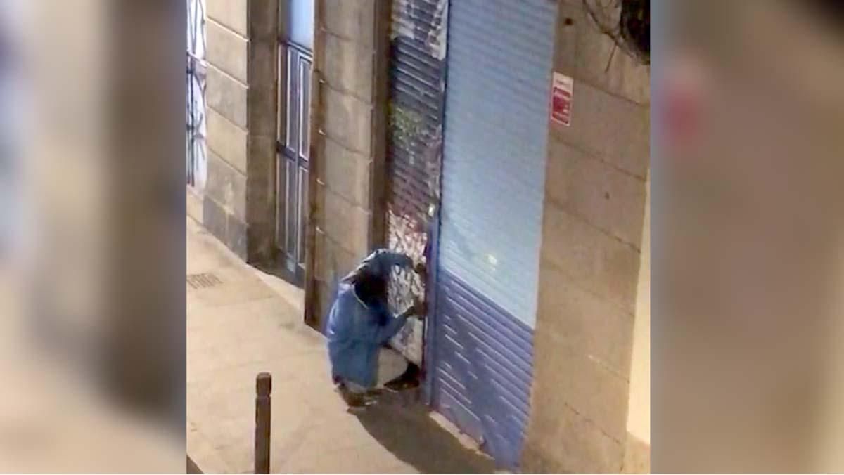 Un home intenta forçar la porta duns baixos abandonats al Raval