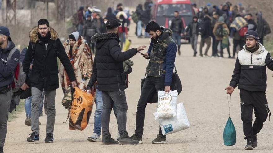 Los migrantes y refugiados que llevan sus pertenencias caminan a lo largo de la frontera turco-griega.