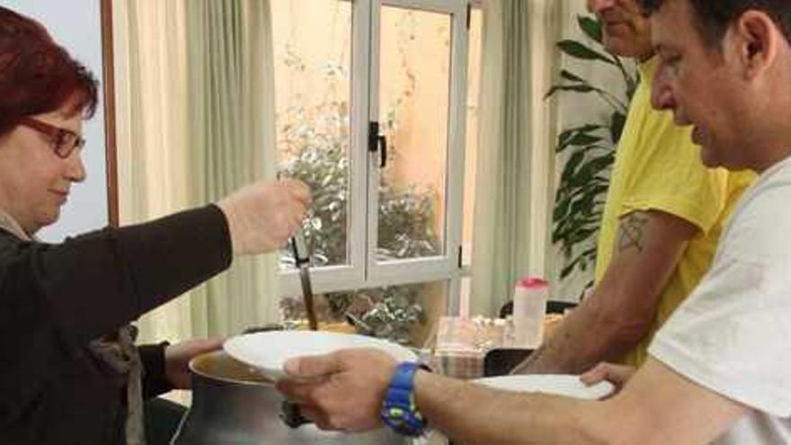 Dos usuarios reciben un plato de comida en el comedor Madre Bonifacia, dependiente de Cáritas Diocesana.