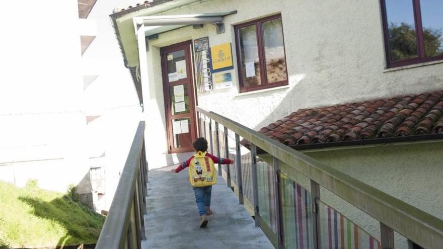 Un niño camina hacia el centro social El Piqueru, local en el que están el telecentro y la nueva ubicación de Correos.