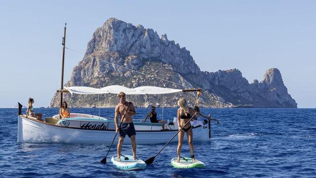 Surcar las cristalinas aguas en un barco tradicional y subirse a la tabla de ‘paddle surf’ alrededor de es Vedrà, un lujo. | FOTOS: SUP YOGA IBIZA