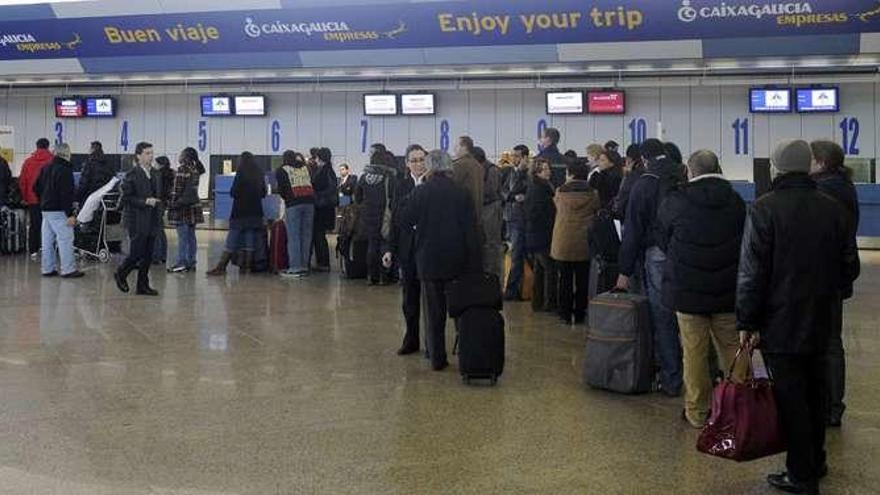 Decenas de pasajeros esperan a facturar sus equipajes en el aeropuerto de Alvedro, el sábado 4 de diciembre de 2010.