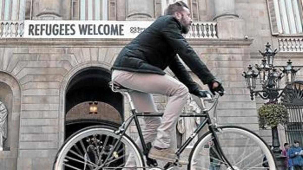 SOLIDARIDAD Un ciclista pasa por delante del Ayuntamiento de Barcelona, donde un cartel da la bienvenida a los refugiados.