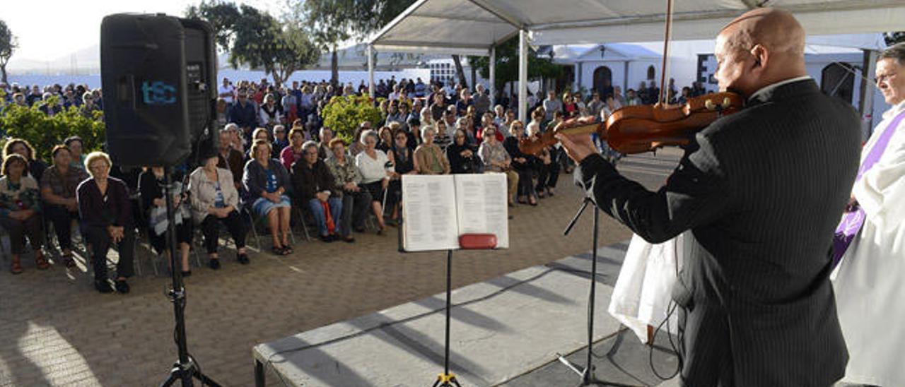 El violinista Pablo Mesa y el párroco de San Ginés, Miguel Hernández, ayer, frente al público en el cementerio.