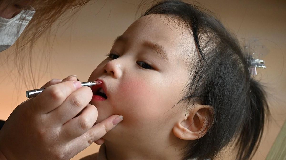 Una niña siendo maquillada por una persona adulta