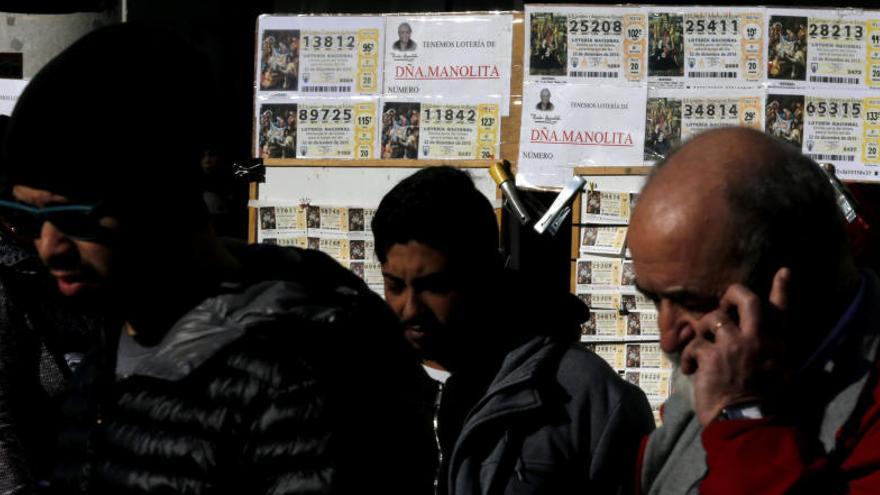 Varias personas junto a unos puestos de Lotería de Navidad.