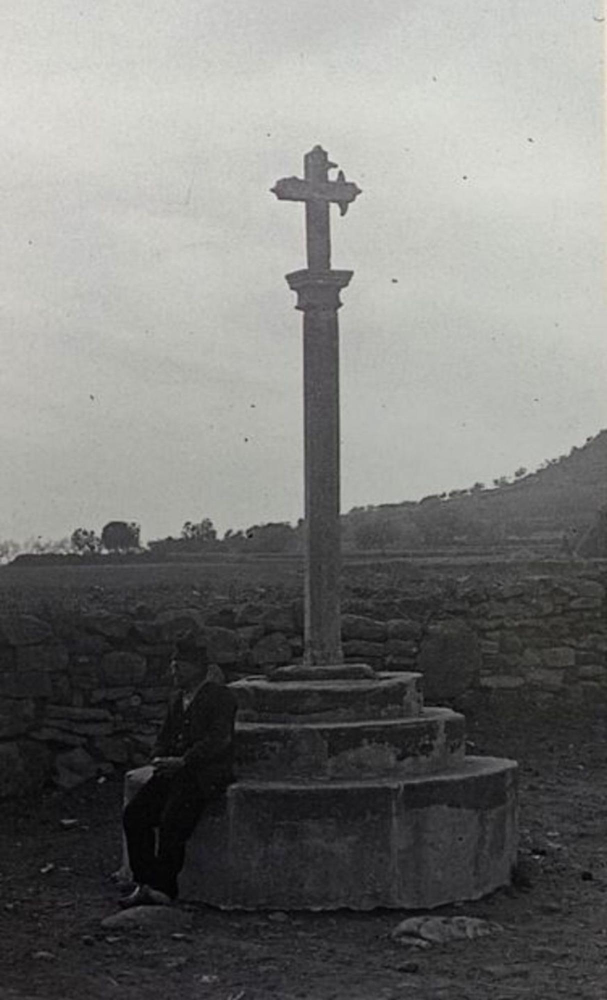 Un home assegut a la base de la Creu de Gualta, també desapareguda; la foto és del 1916.