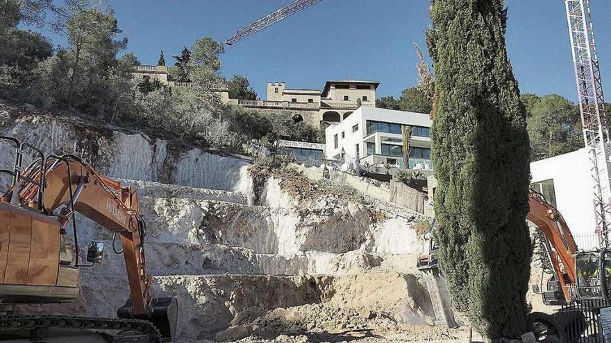 Una excavadora extrae material de la montaña para allanar el solar.