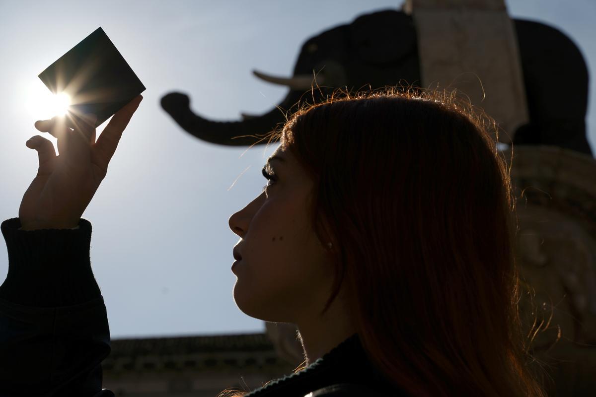 Una chica observa el eclipse parcial de luna desde la plaza del Duomo de la localidad siciliana de Catania.