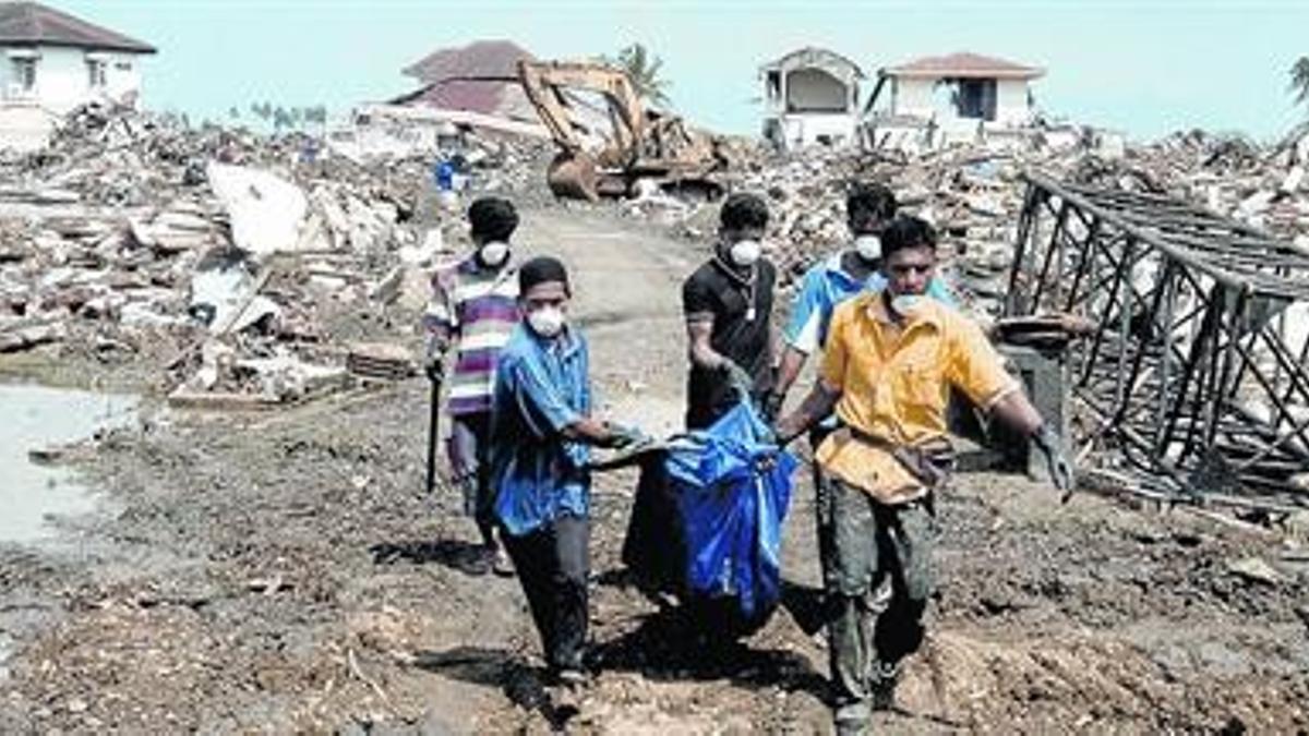 Voluntarios trasladan cadáveres de Ule Lhee, en Banda Aceh, en enero del 2005.