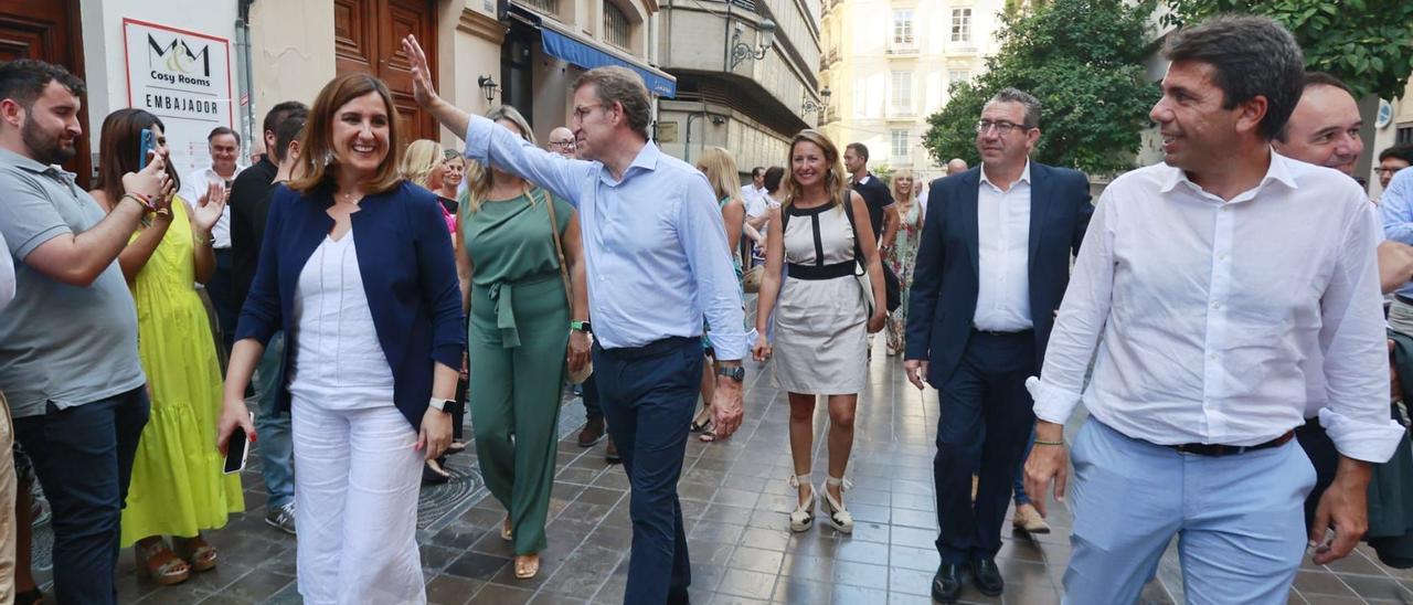 El presidente del PP, Alberto Núñez Feijóo, saluda ayer en València, junto a Carlos Mazón y María José Catalá, en el trayecto a pie hacia la nueva sede autonómica del PP. | FERNANDO BUSTAMANTE