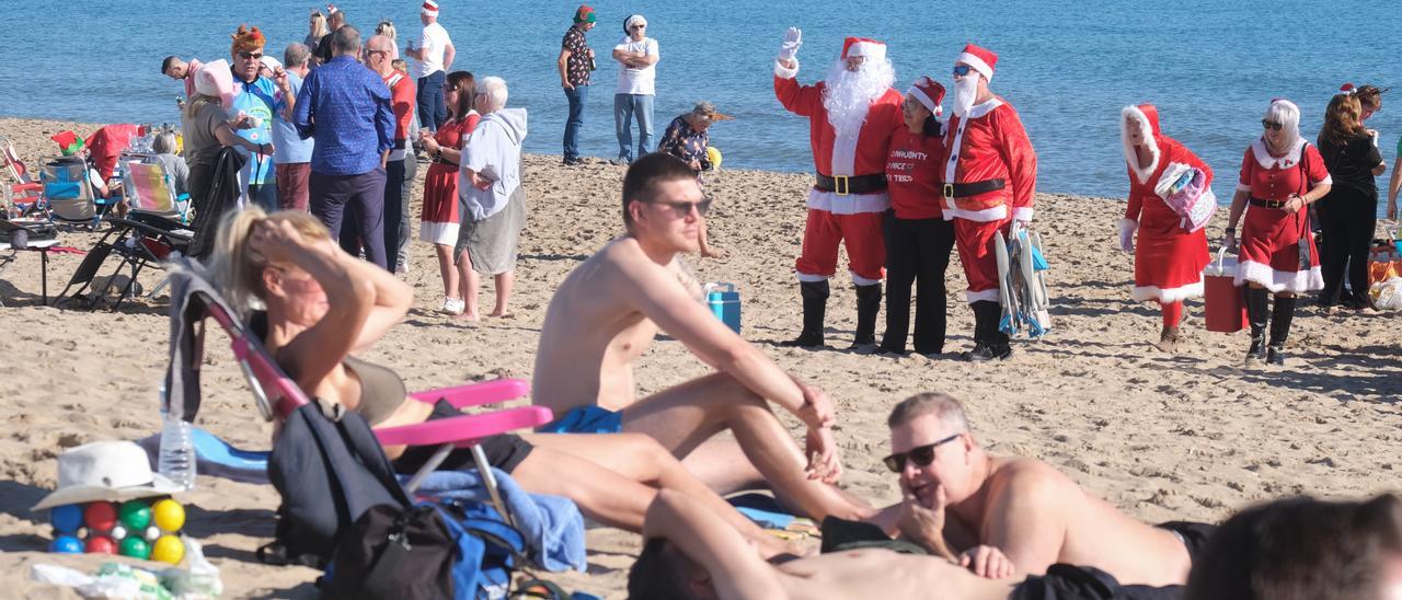 Una playa del sur de la provincia las pasadas Navidades, con personas vestidas de Papá Noel junto a otras tomando el sol en bañador.