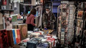 Un hombre recoge un libro encargado previamente en una librería de París, el pasado sábado.