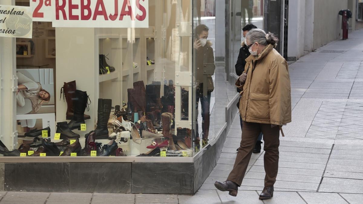 Viandantes echan un vistazo al escaparate de un comercio de Mérida.