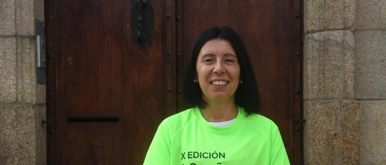 Ana M” Amido, con la camiseta que hoy lucirá en la ‘andaina’ de la AECC, junto a la entrada de la sede de la asociación, en la Marina coruñesa.