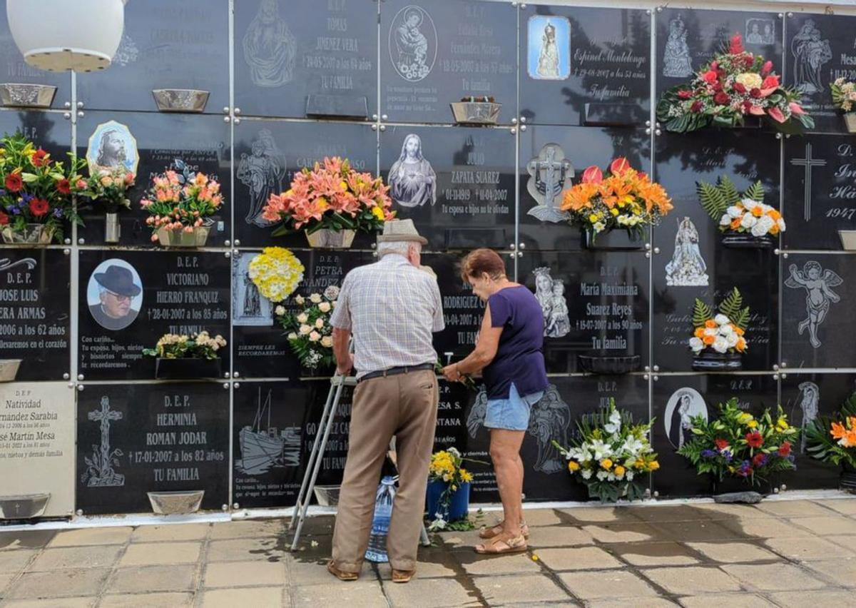 Una pareja limpia una lápida y deposita flores a sus seres queridos en La Oliva. | | LP/DLP