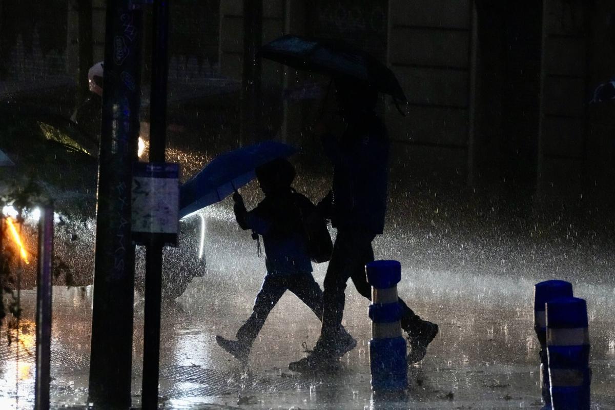 Pluja intensa i gent amb paraigua durant una tempesta a Barcelona.