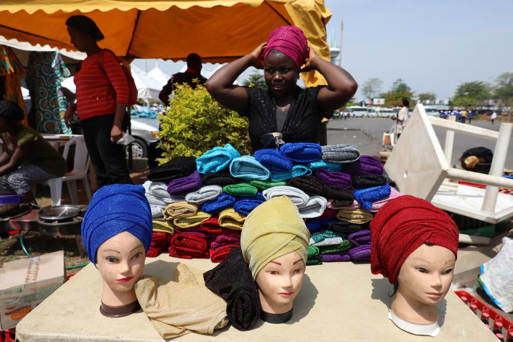 A woman adjusts her headdress as she tends her ...