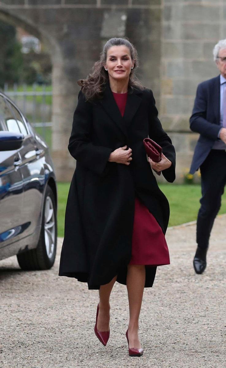 El look de la reina Letizia con abrigo negro y vestido burdeos, todo de Carolina Herrera